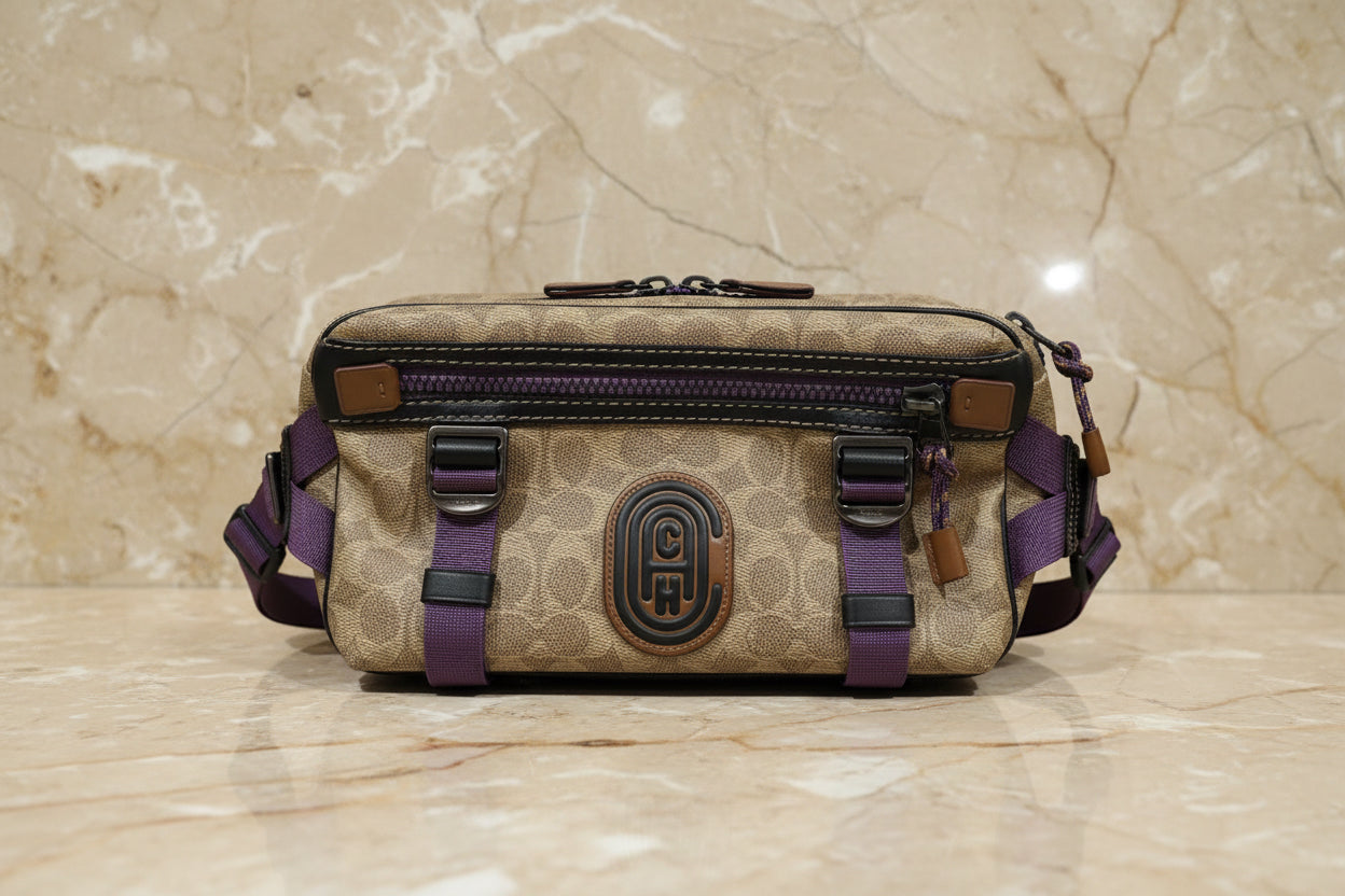 حقيبة خصر/حقيبة جسم محدودة الإصدار مطبوعة بشعار كوتش، مصنوعة من قماش الكانفاس البني المميز.