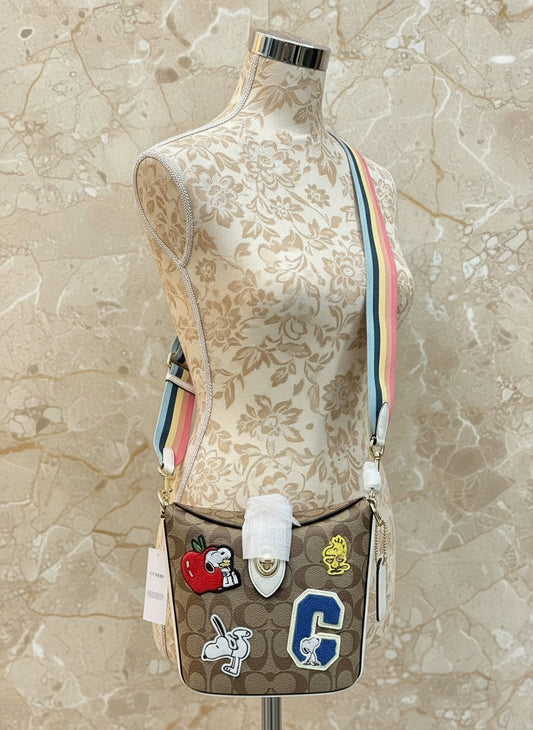 حقيبة كروسبودي من كوتش × بيناتس آدي مصنوعة من قماش الكانفاس المميز والجلد مع رقع رياضية